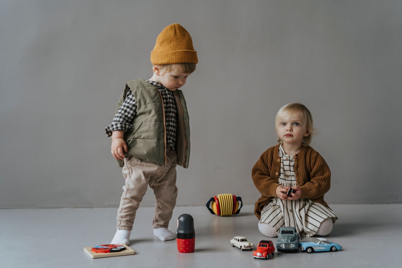 Two young children in checked and striped clothing playing with toys.